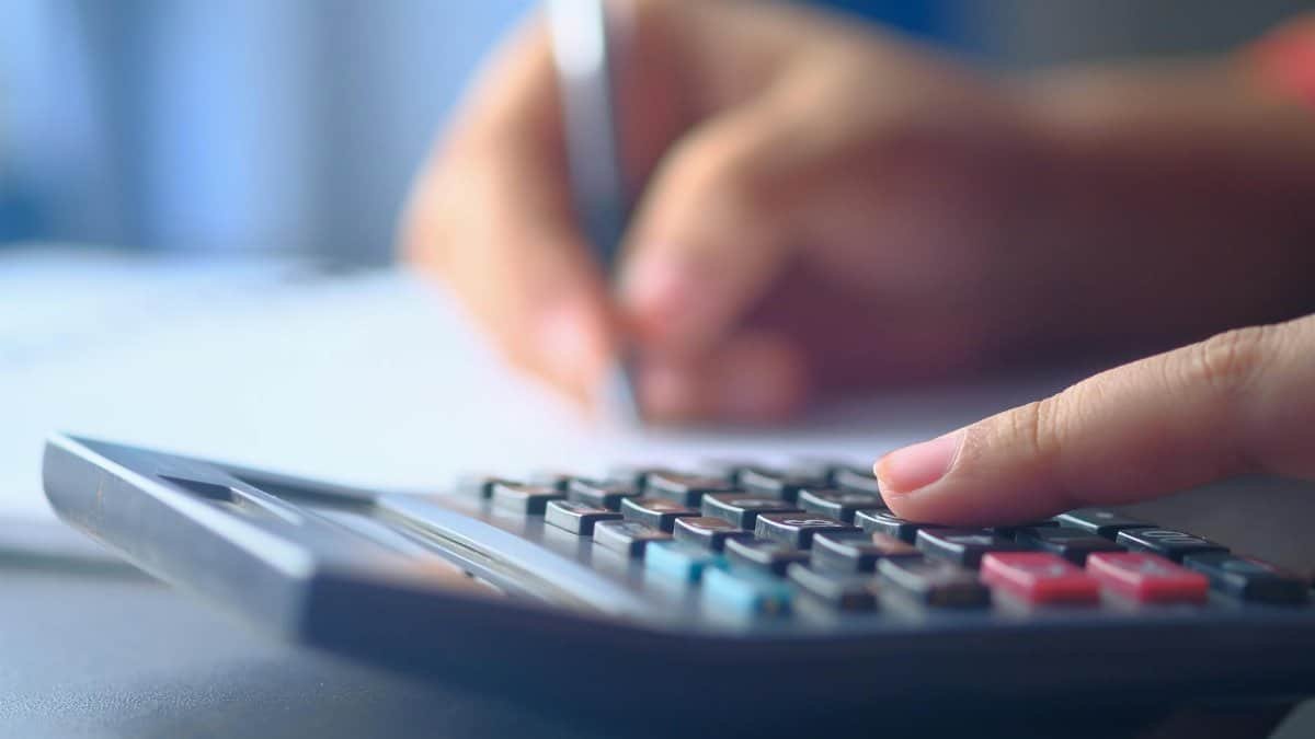A close-up image of hands working on a calculator and writing, representing budgeting and financial planning.
