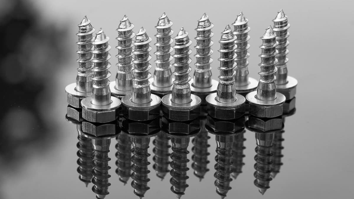 Close-up of shiny metal screws reflecting on a glossy surface. Ideal for industrial or construction themes.