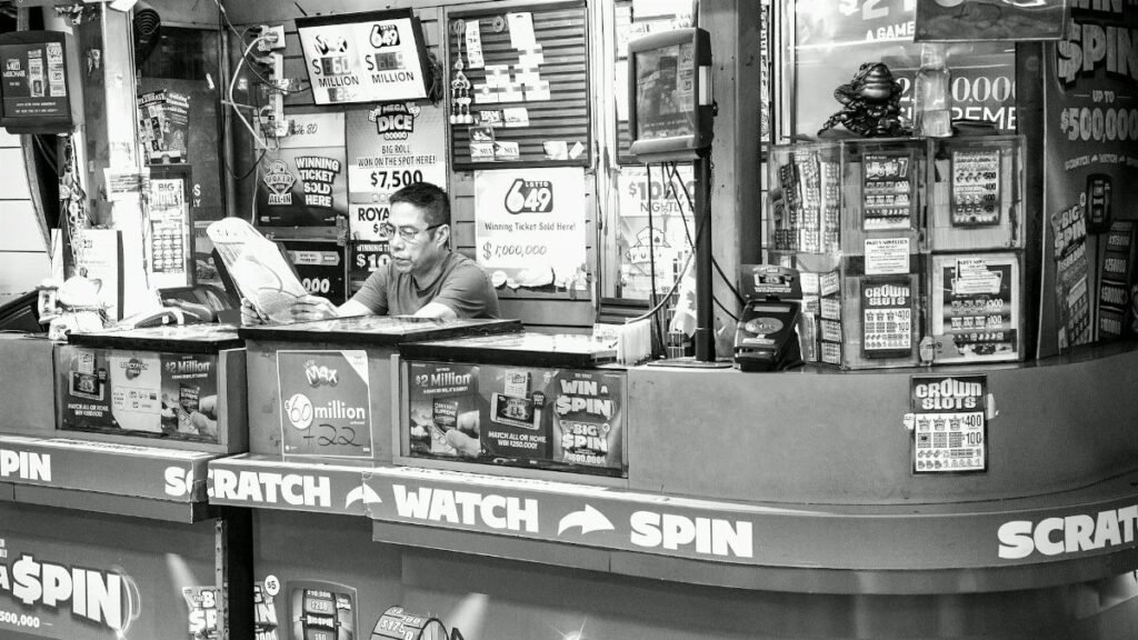 A man reads at a busy lottery ticket booth filled with signs and advertisements.