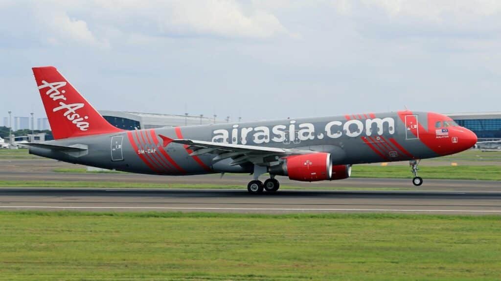 AirAsia plane taking off on runway at a busy airport, showcasing aviation and travel.