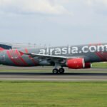 AirAsia plane taking off on runway at a busy airport, showcasing aviation and travel.