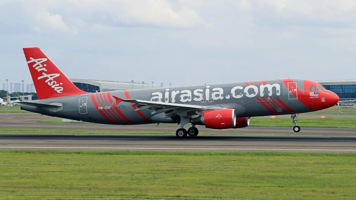 AirAsia plane taking off on runway at a busy airport, showcasing aviation and travel.