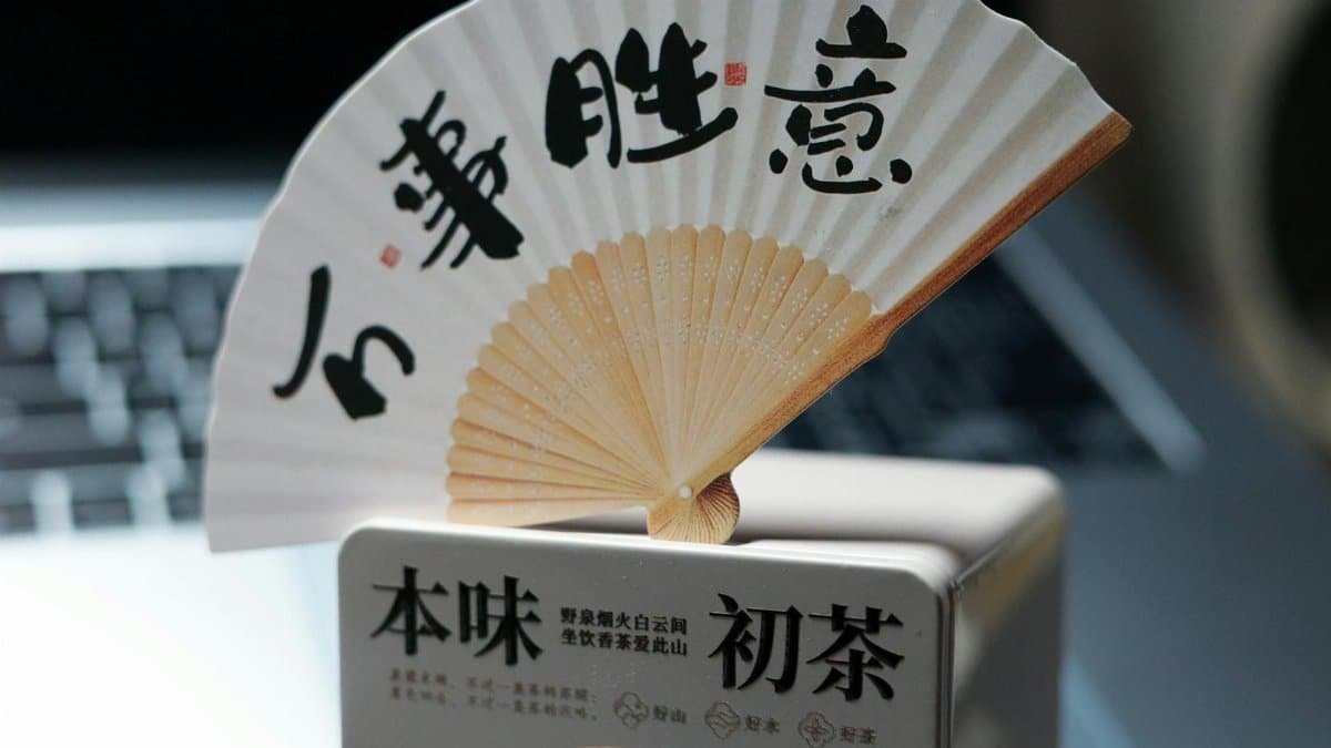 Close-up of a beautiful Asian paper fan featuring calligraphy, highlighting cultural elegance.
