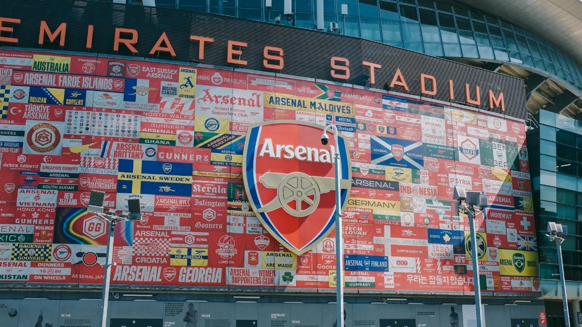 Vibrant wall art at Emirates Stadium featuring Arsenal flags and crest in London, UK.
