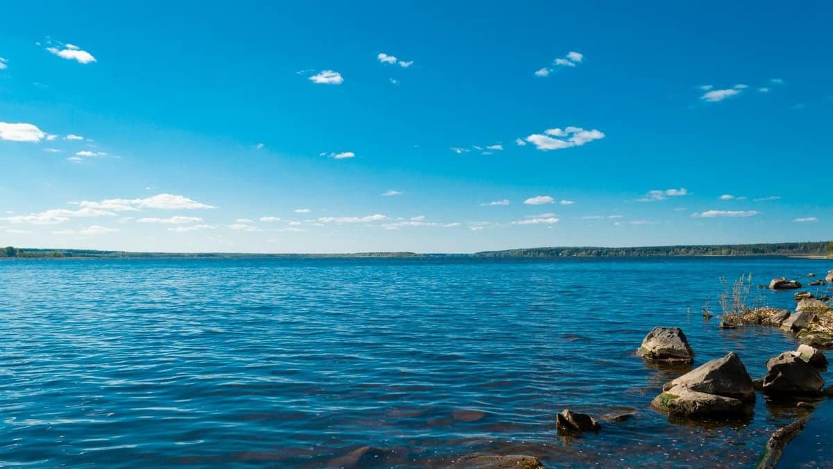 Serene view of a blue lake with rocky shore under a clear blue sky, ideal for nature lovers.