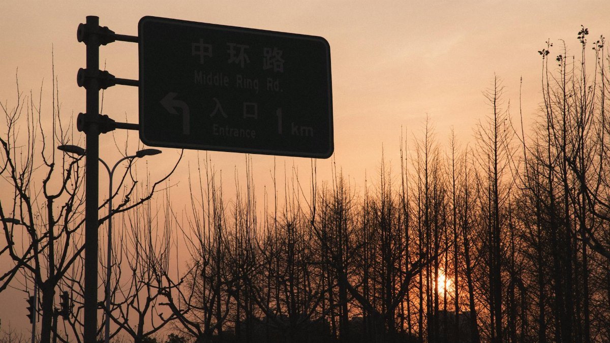 Silhouette of a road sign with sunset backdrop in urban setting.
