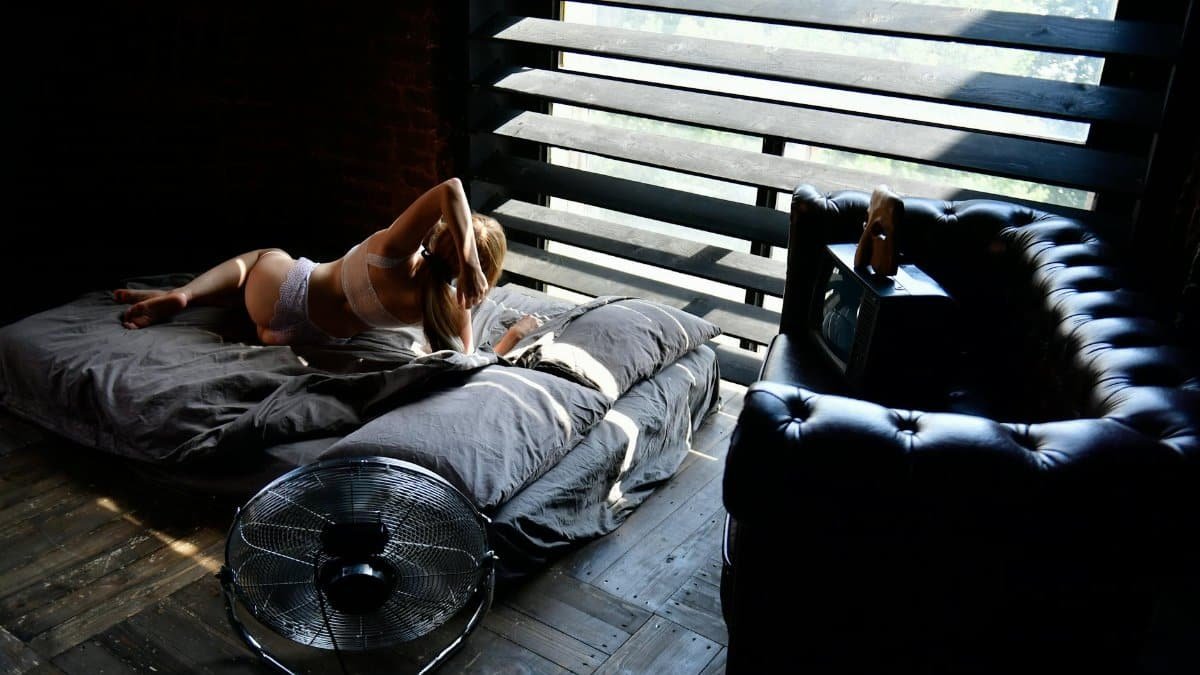 A tranquil bedroom scene with a woman relaxing in soft natural light, creating a peaceful atmosphere.