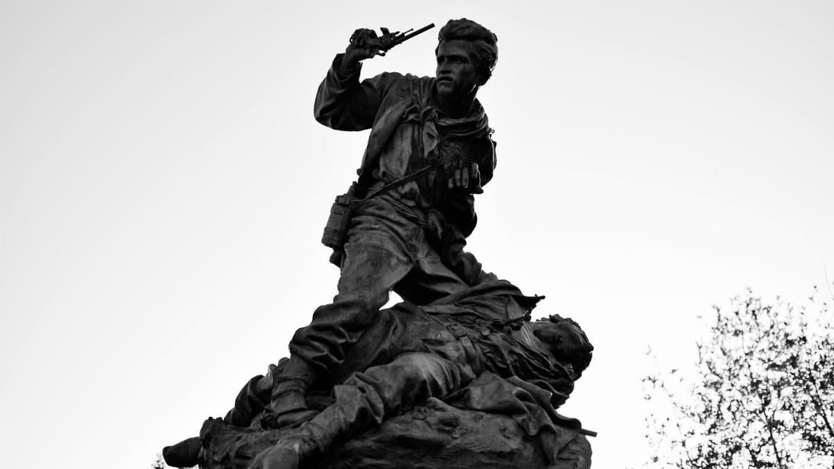 Monumental sculpture depicting a dramatic war scene with two soldiers in black and white, capturing historical intensity.
