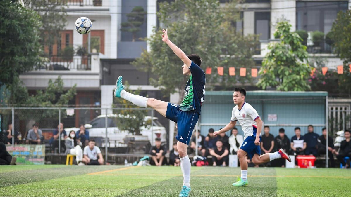 Action-packed football match in Hanoi with two players competing intensely on the turf.