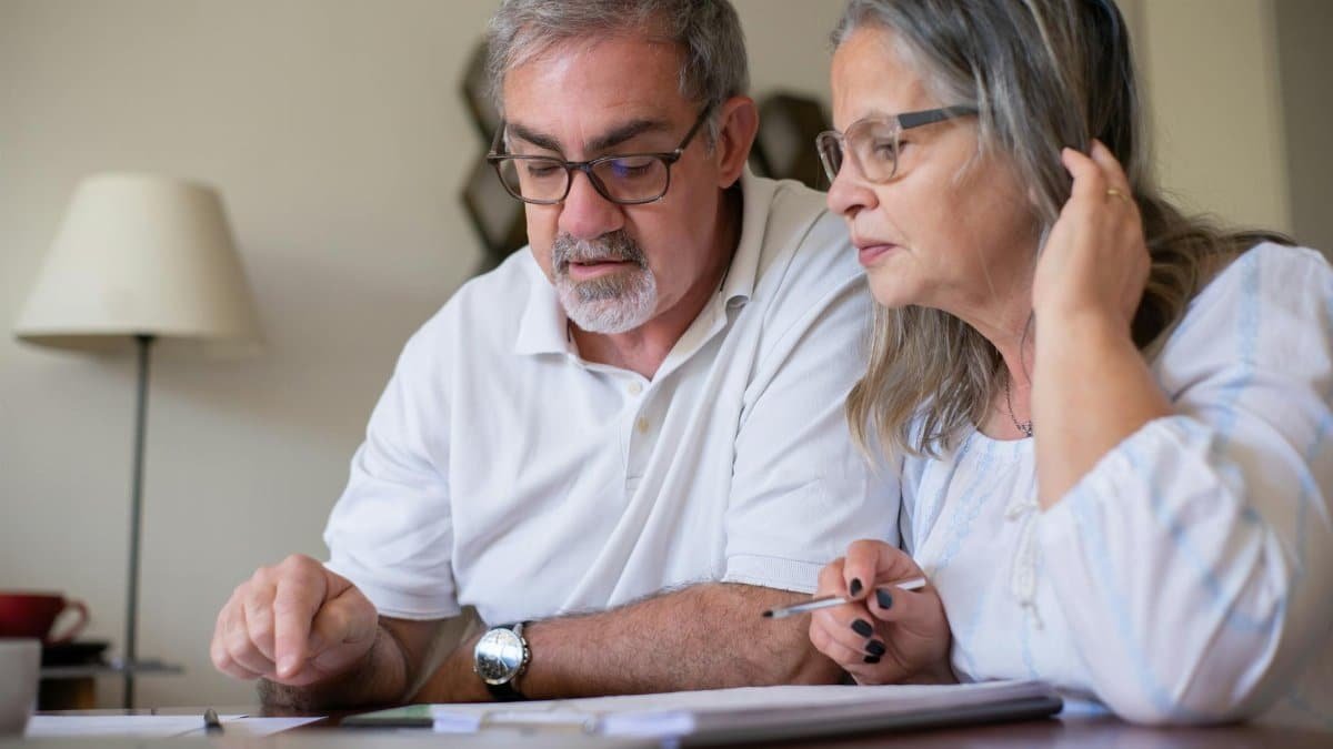 Elderly couple enjoying leisure time with crosswords at home, showcasing togetherness.