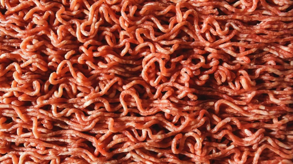 Detailed close-up image of raw, red ground beef with visible strands.