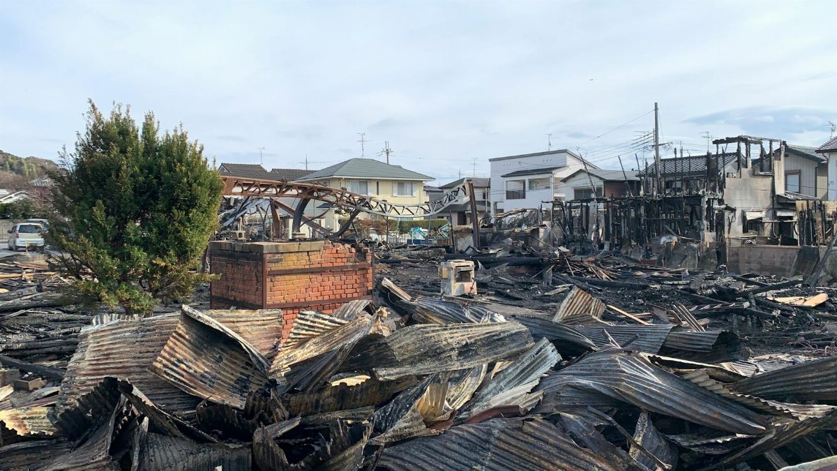 A scene showing destroyed buildings and debris after a large fire in an urban neighborhood.