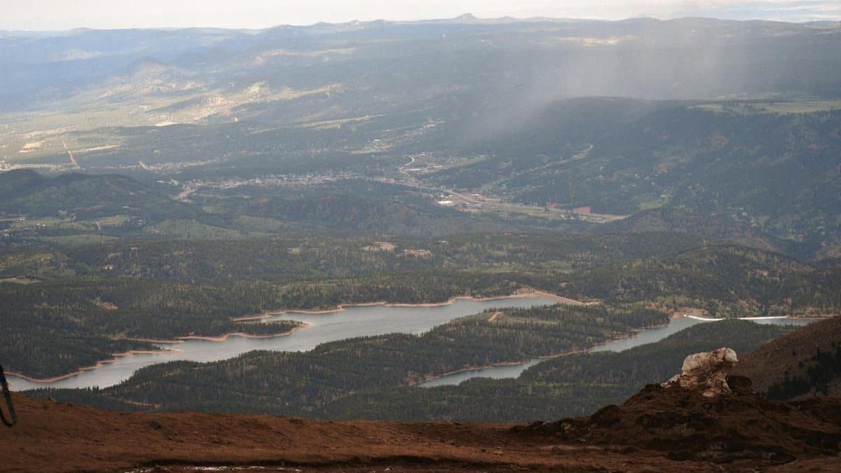 Scenic view from Pikes Peak summit showcasing expansive forested valley and reservoir.