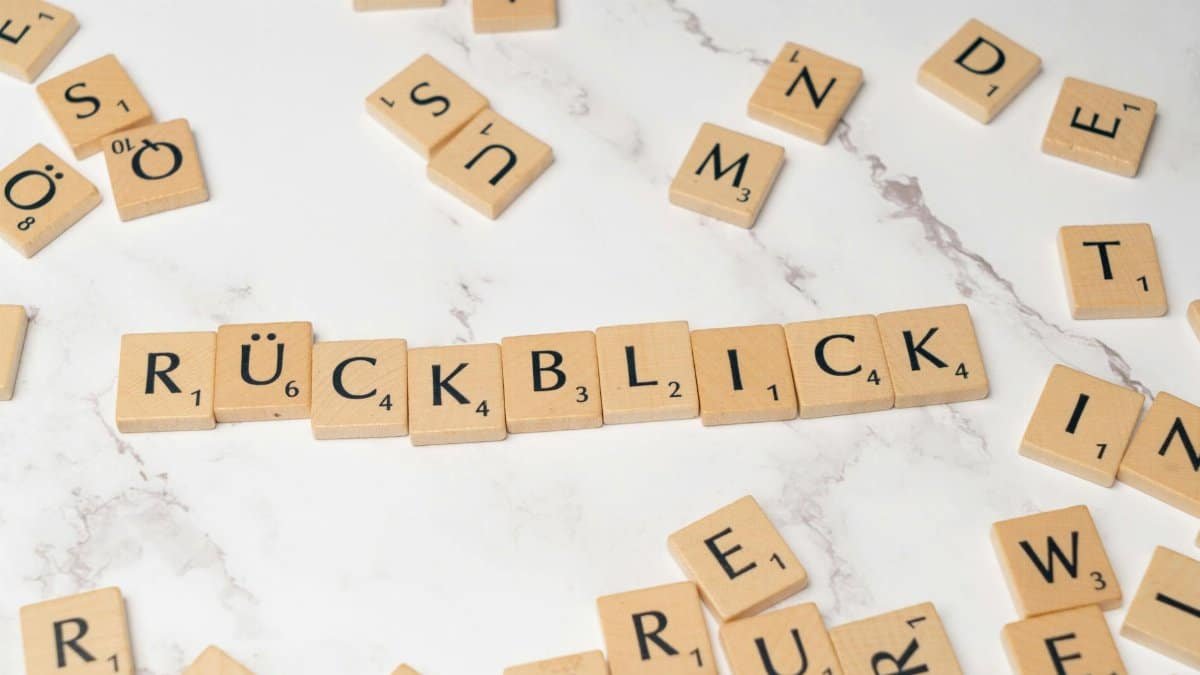 High-angle shot of wooden letter tiles spelling 'Rückblick' on a marble background.