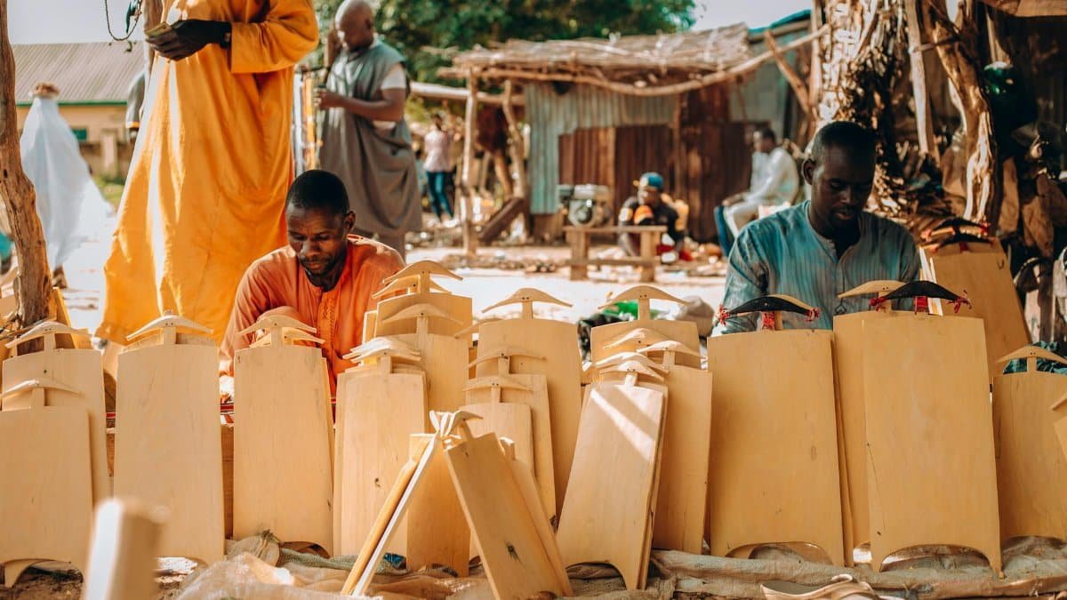 Artisans at work crafting wooden items in an outdoor market setting, showcasing traditional craftsmanship.