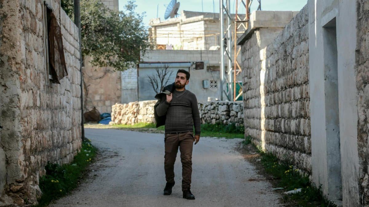 A man walks through a stone-lined alley in Idlib, Syria, showcasing local architecture.