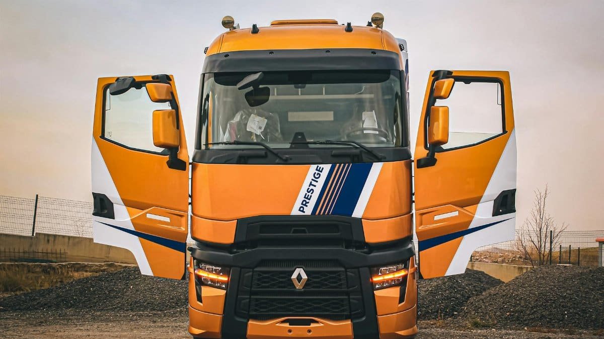 Front view of an orange Renault truck with open doors parked in a rural area.