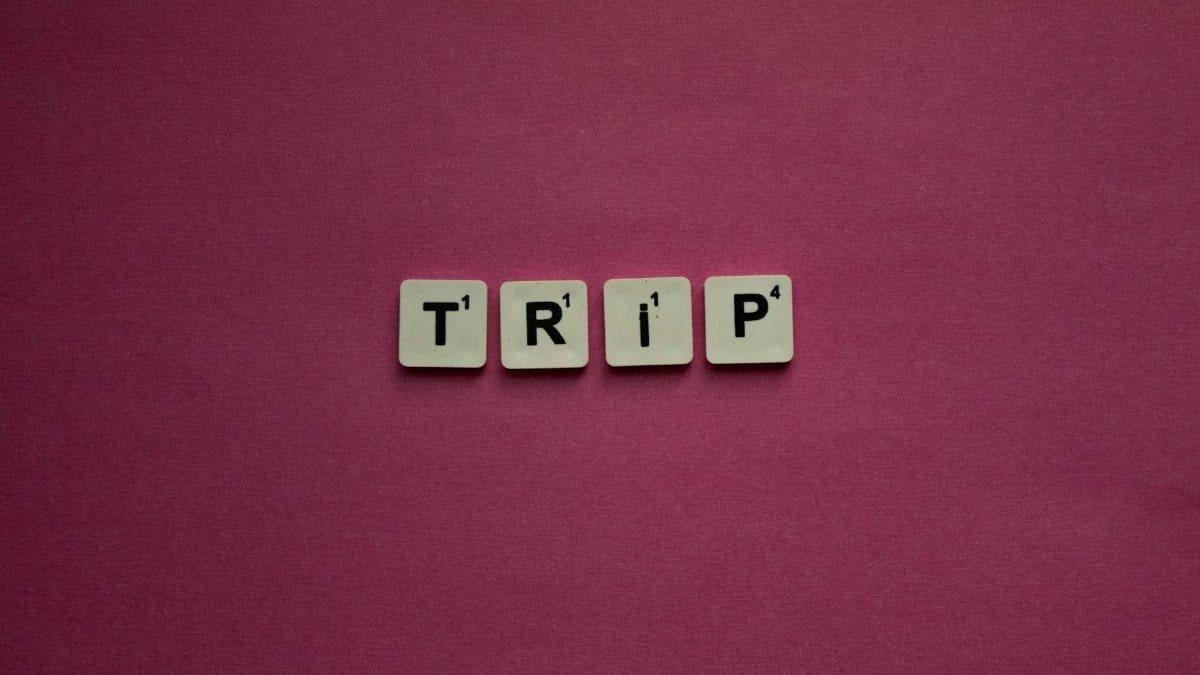 Scrabble tiles spelling 'TRIP' on a pink background, perfect for travel themes.