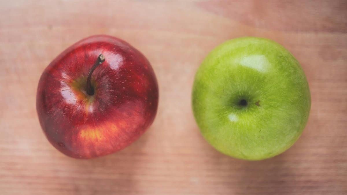 Close-up of a red and a green apple on a wooden table, ideal for healthy eating themes.