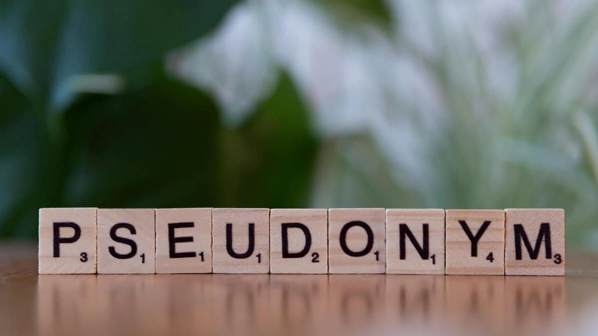 Wooden letter tiles spelling 'Pseudonym' on a table with a blurred background.