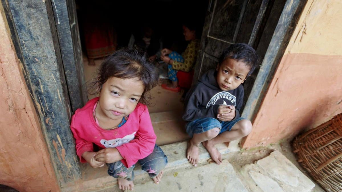 Curious children sitting in a doorway, looking up with inquisitive expressions.