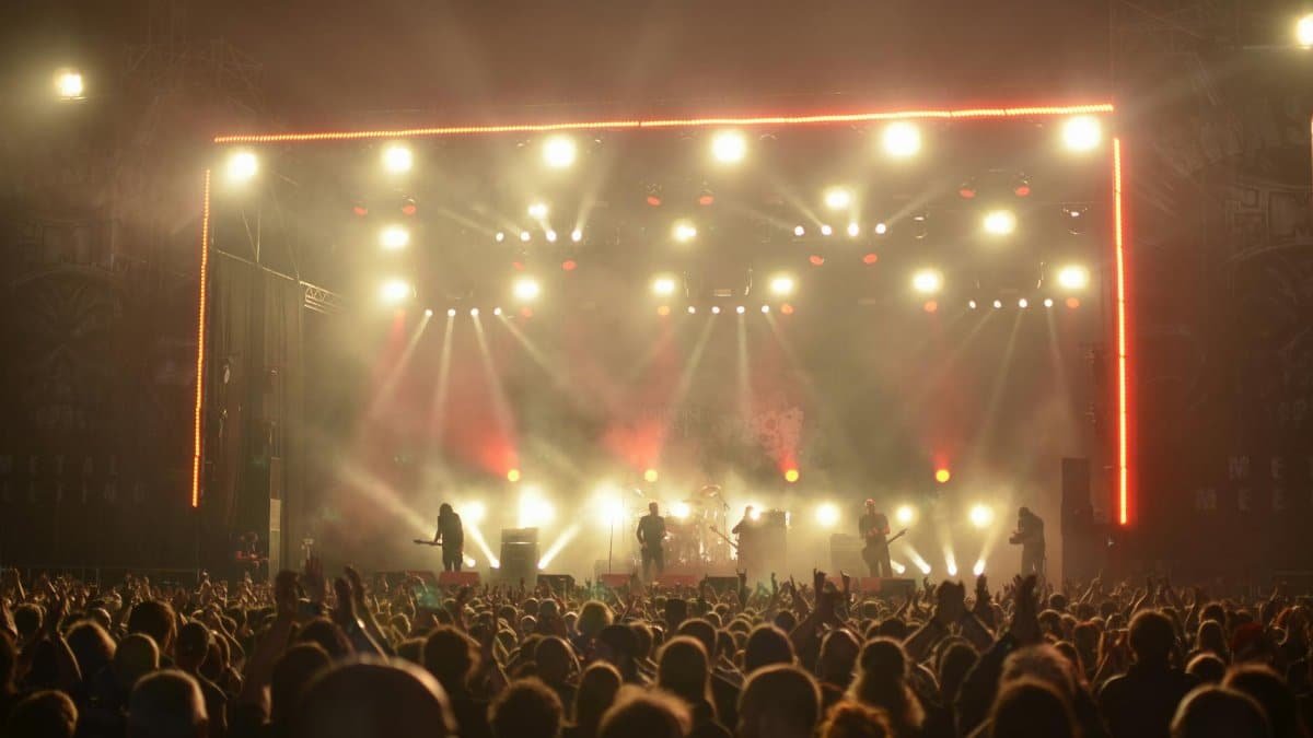 Dynamic live concert with band on stage, lighting effects, and enthusiastic crowd at night.