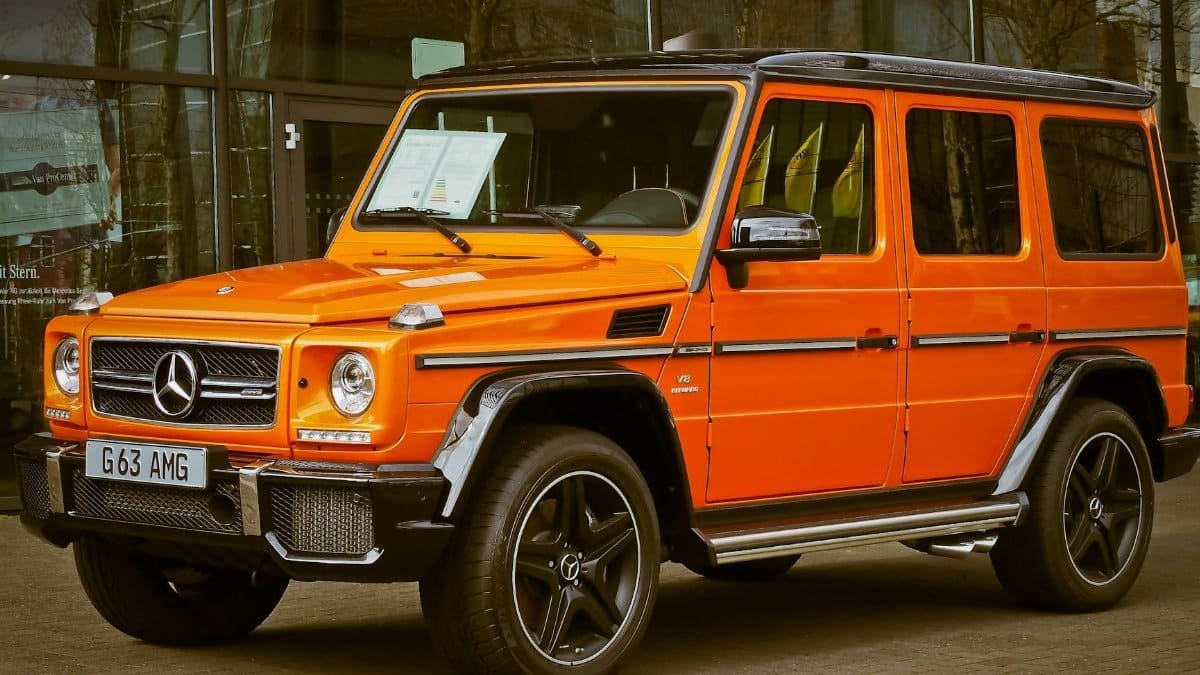Bright orange Mercedes-Benz G Wagon parked in front of a building, showcasing luxury and style.