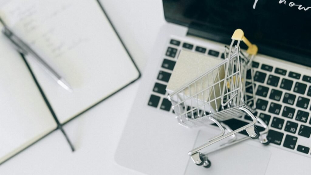 Creative depiction of online shopping with a miniature cart on a laptop keyboard.