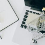 Creative depiction of online shopping with a miniature cart on a laptop keyboard.