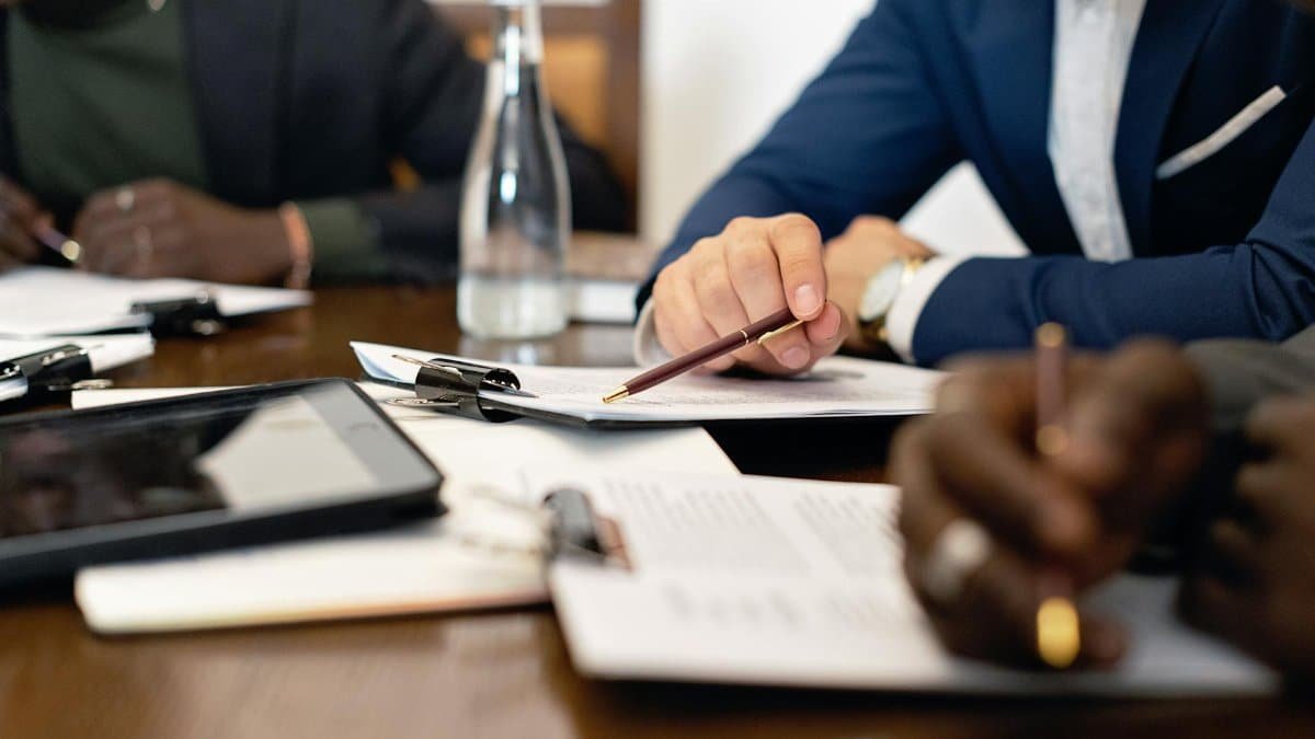 Business meeting with adults discussing and signing contracts over a table.