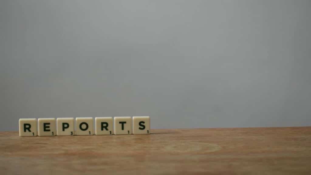 Scrabble tiles spelling 'reports' on a wooden desk, ideal for office or business themes.