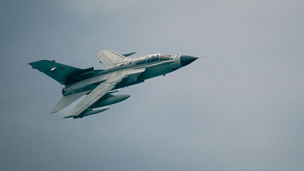 A Panavia Tornado combat aircraft soaring through a cloudy sky, showcasing power and speed.