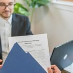 Mortgage broker and client discussing loan application with documents on table.