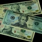 High angle view of US 10 and 20 dollar bills on a black background, emphasizing finance and currency themes.