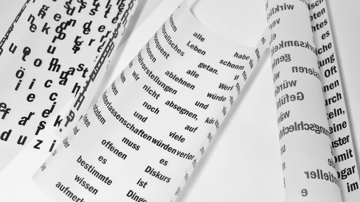 From above of rolled sheets of paper with inscriptions written in German language placed on white background in light room