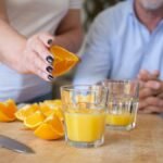 A person preparing fresh orange juice on a chopping board indoors, showcasing healthy lifestyle.