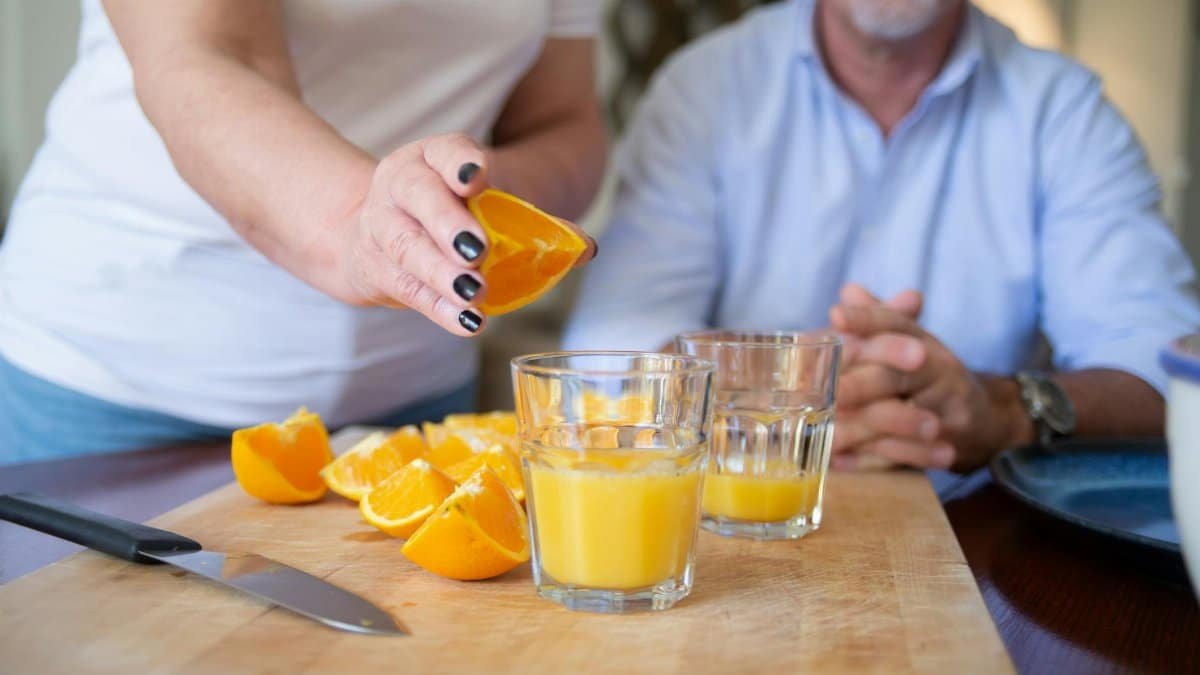 A person preparing fresh orange juice on a chopping board indoors, showcasing healthy lifestyle.
