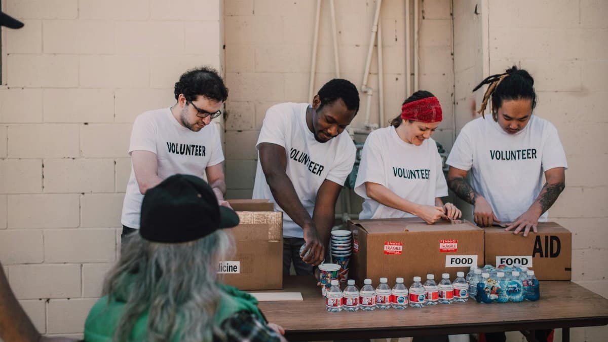 Group of volunteers organizing and distributing aid packages and bottled water outdoors.