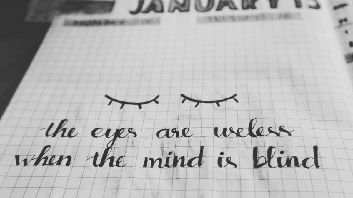 Black and white notebook page with an inspirational quote and eye illustration on a grid background.