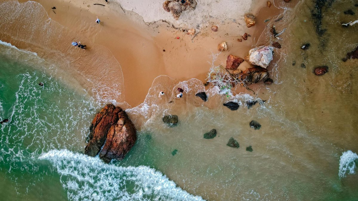 Stunning aerial shot of Chukai Beach, Terengganu, showcasing vibrant waves and rocky shores.