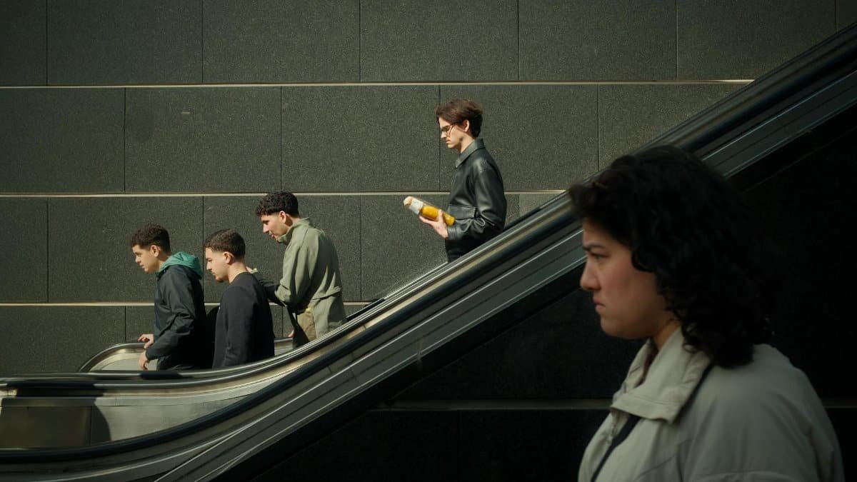 City dwellers contrast with architectural elements as they navigate a mall escalator.