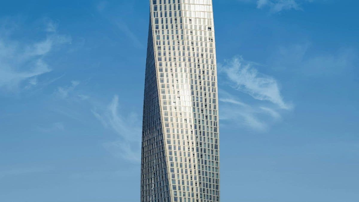 Elegant twisting skyscraper highlighted against a pristine blue sky, showcasing modern architectural design.