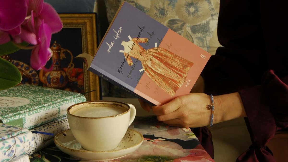 A serene scene of holding a book with a cup of coffee on a florally decorated table.