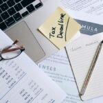 Workspace with laptop, documents, and tax deadline note for financial management.