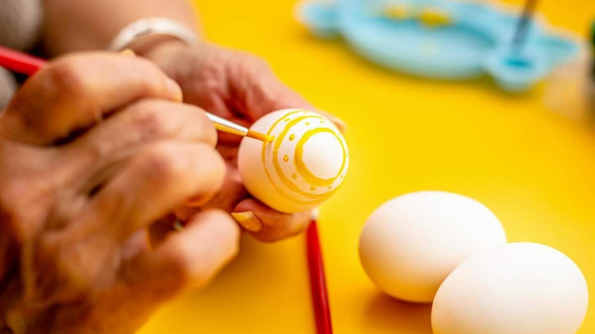 Close-up of hands painting Easter eggs with bright colors, creative and festive.