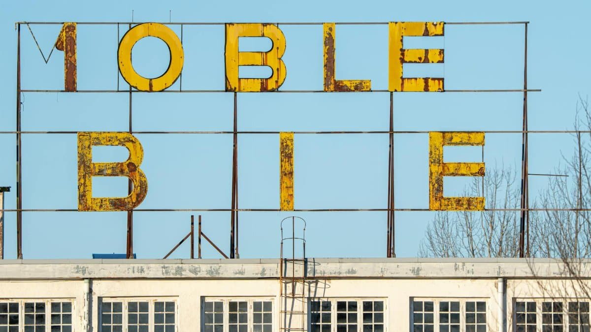 Weathered industrial sign on a rooftop against a clear sky, showcasing urban decay.