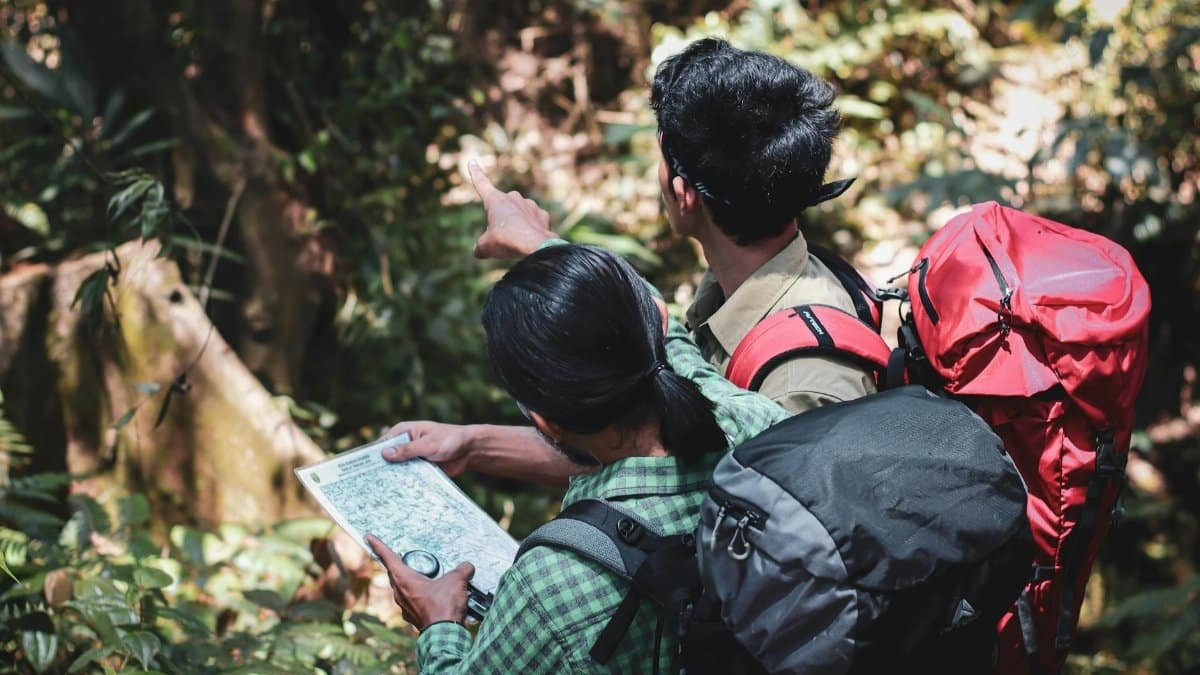 Two backpackers navigating a forest trail, using a map to find their way.