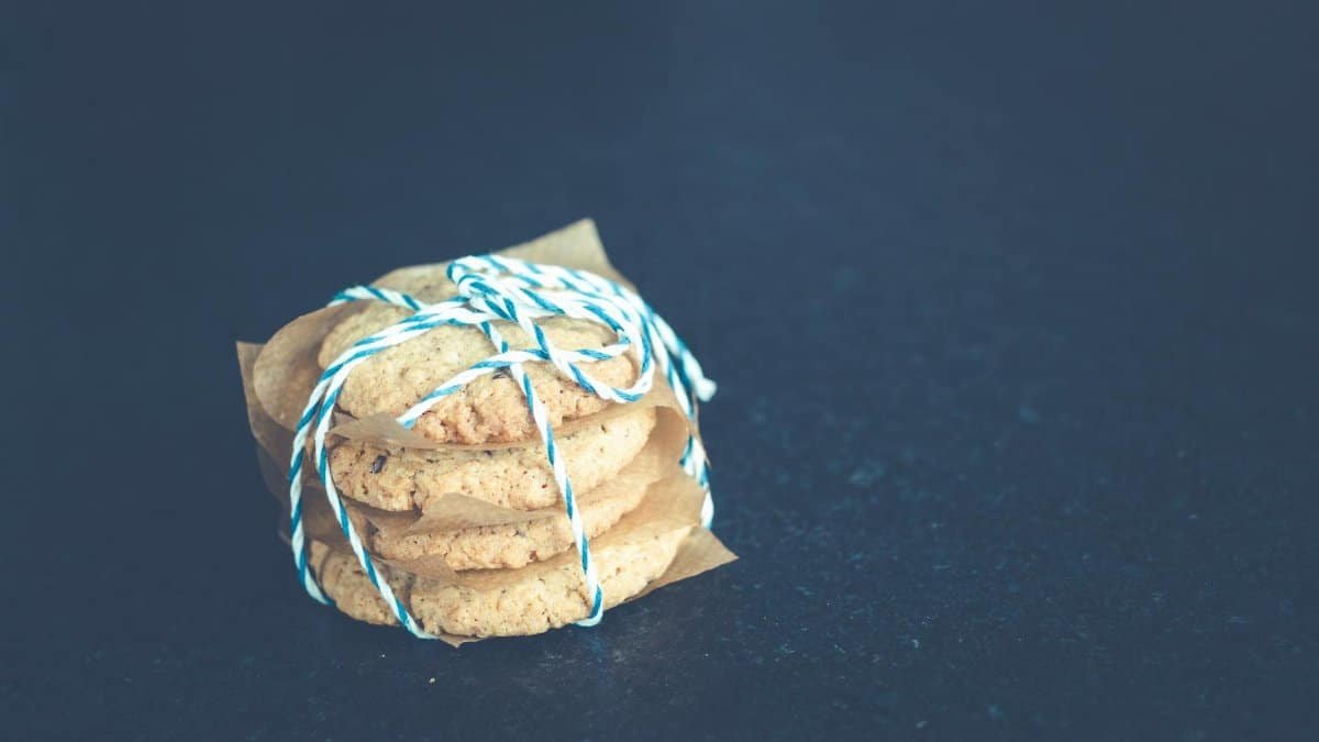 A neatly stacked pile of homemade cookies tied with colorful string on a dark surface.