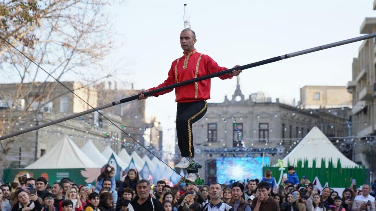A skilled tightrope walker performing above a crowd at an outdoor festival, captivating the audience.