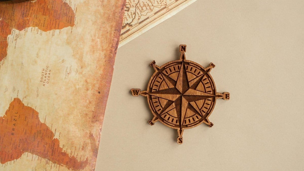 Wooden compass rose and vintage map on beige background, perfect for travel themes.